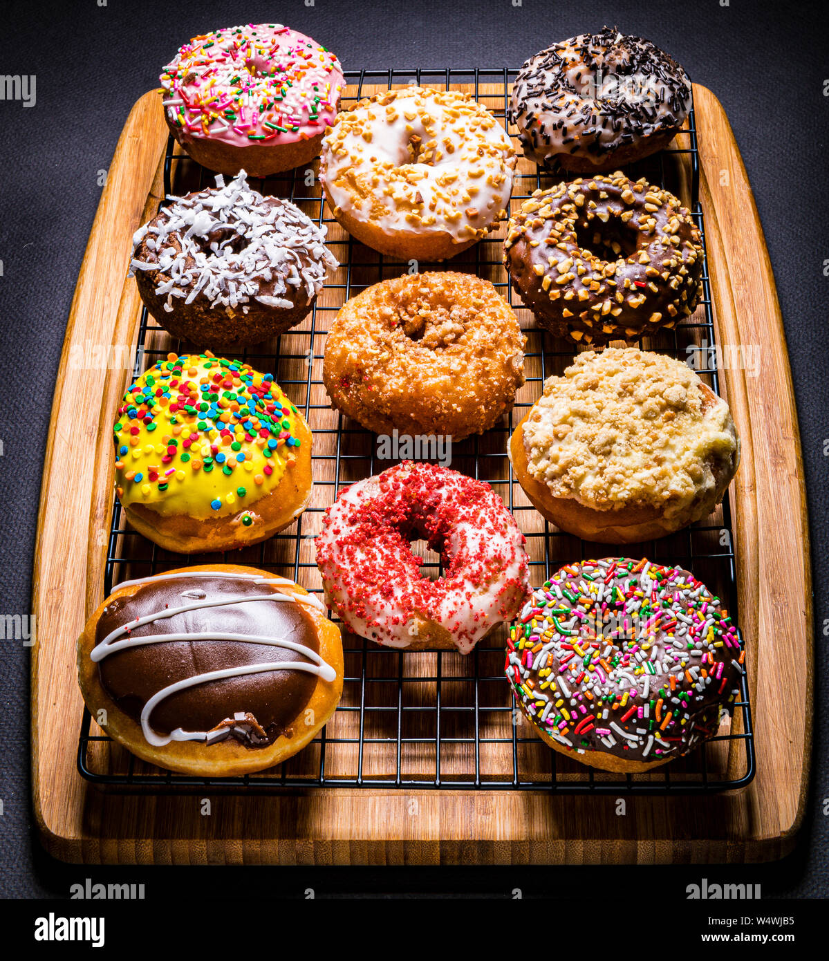assorted donuts on wire rack on wooden cutting board Stock Photo