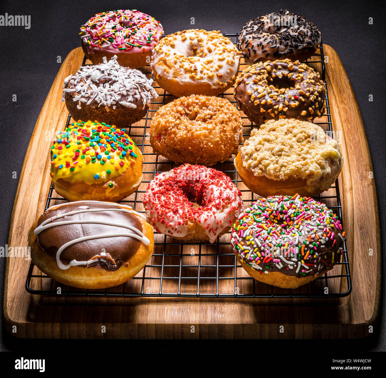 assorted donuts on wire rack on wooden cutting board Stock Photo