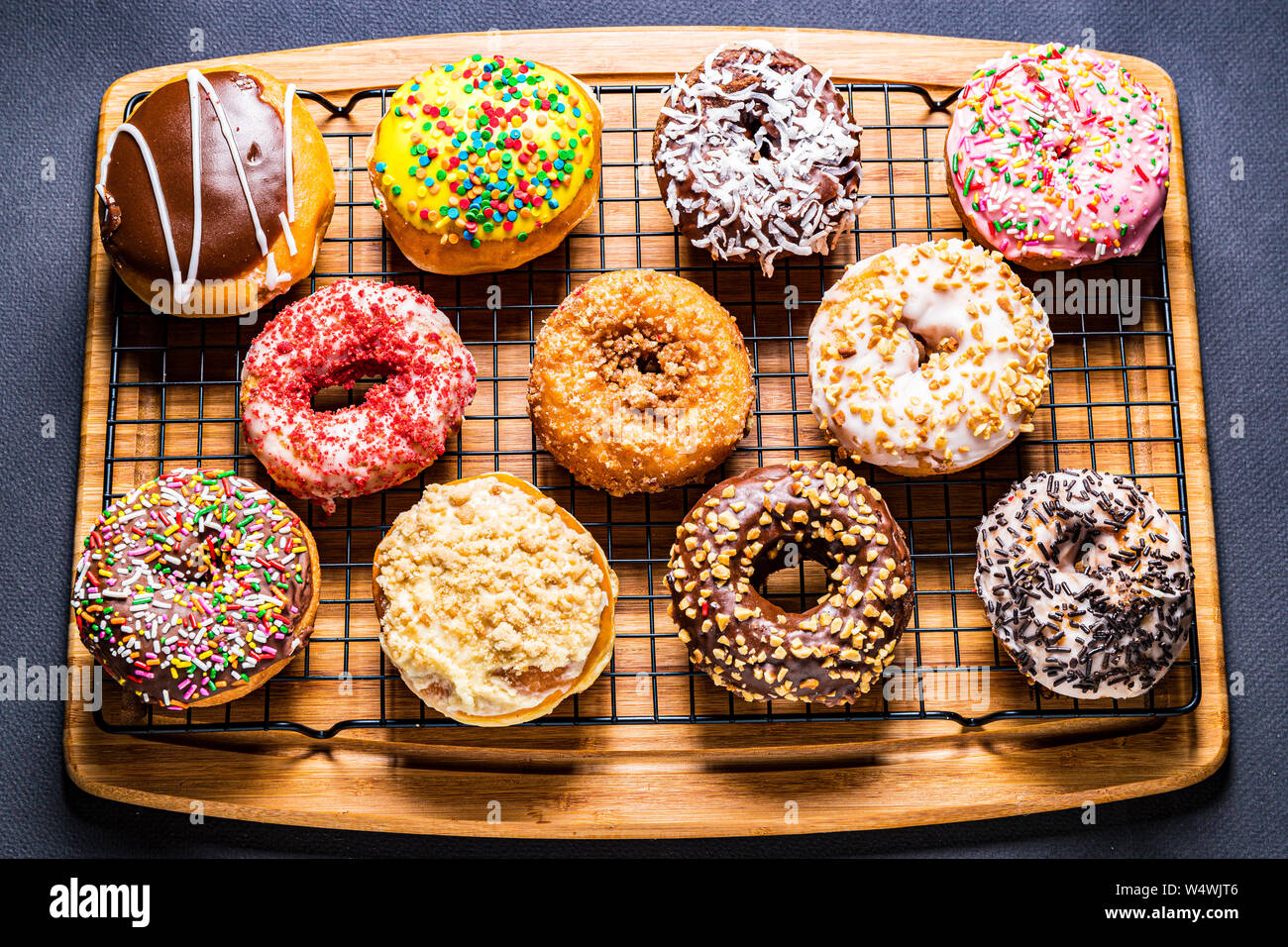 assorted donuts on wire rack on wooden cutting board Stock Photo