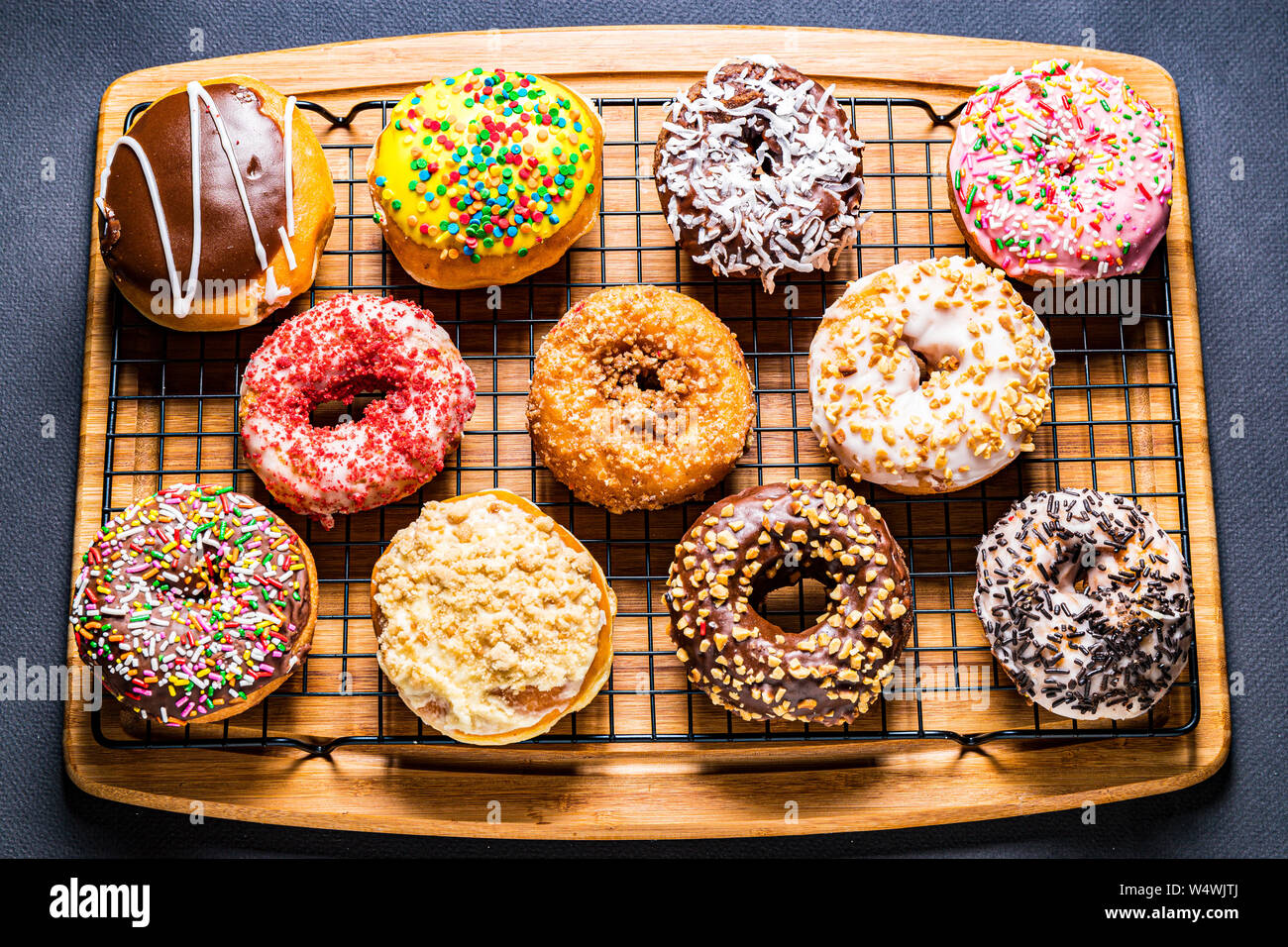 assorted donuts on wire rack on wooden cutting board Stock Photo