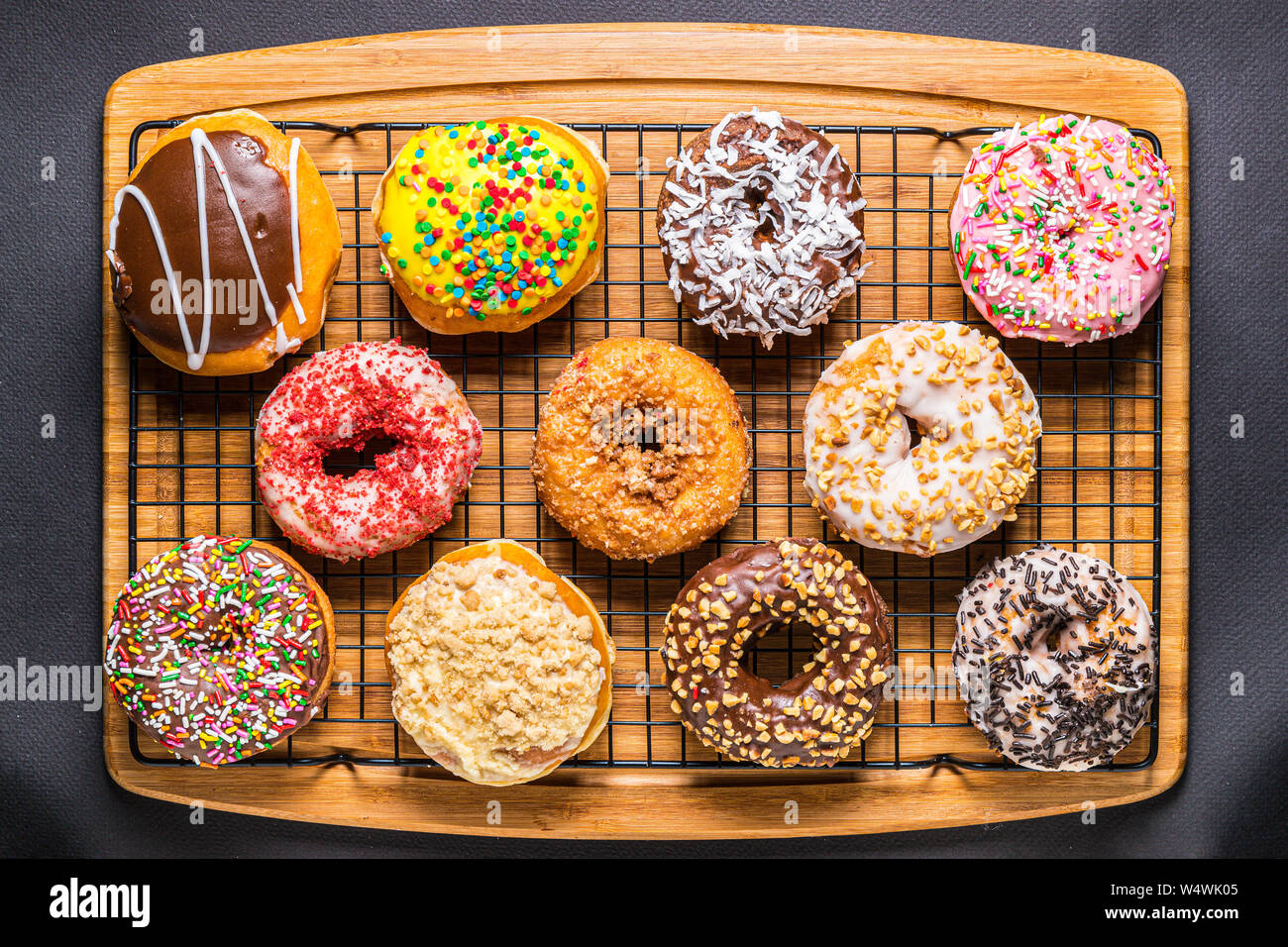 assorted donuts on wire rack on wooden cutting board Stock Photo