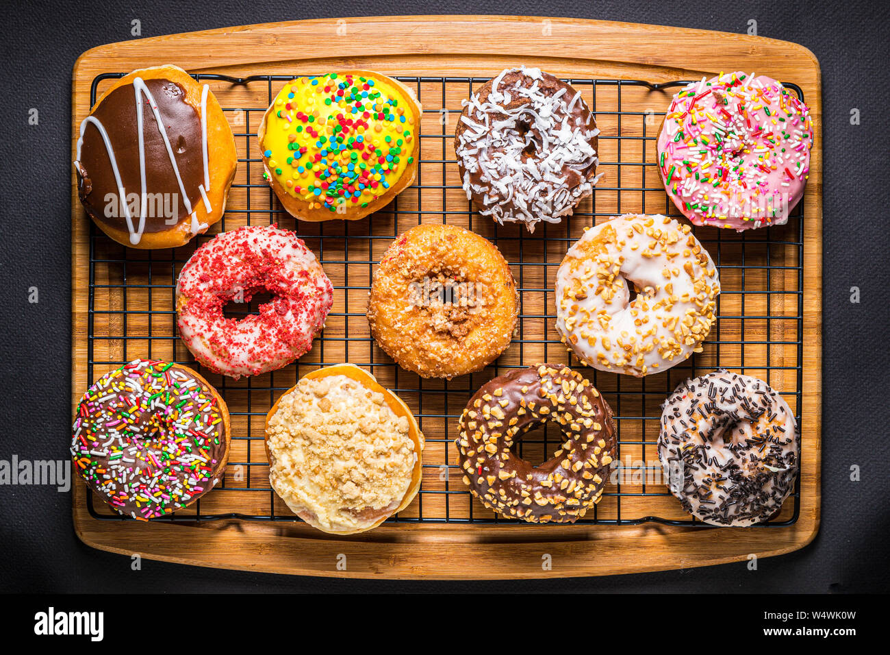 assorted donuts on wire rack on wooden cutting board Stock Photo