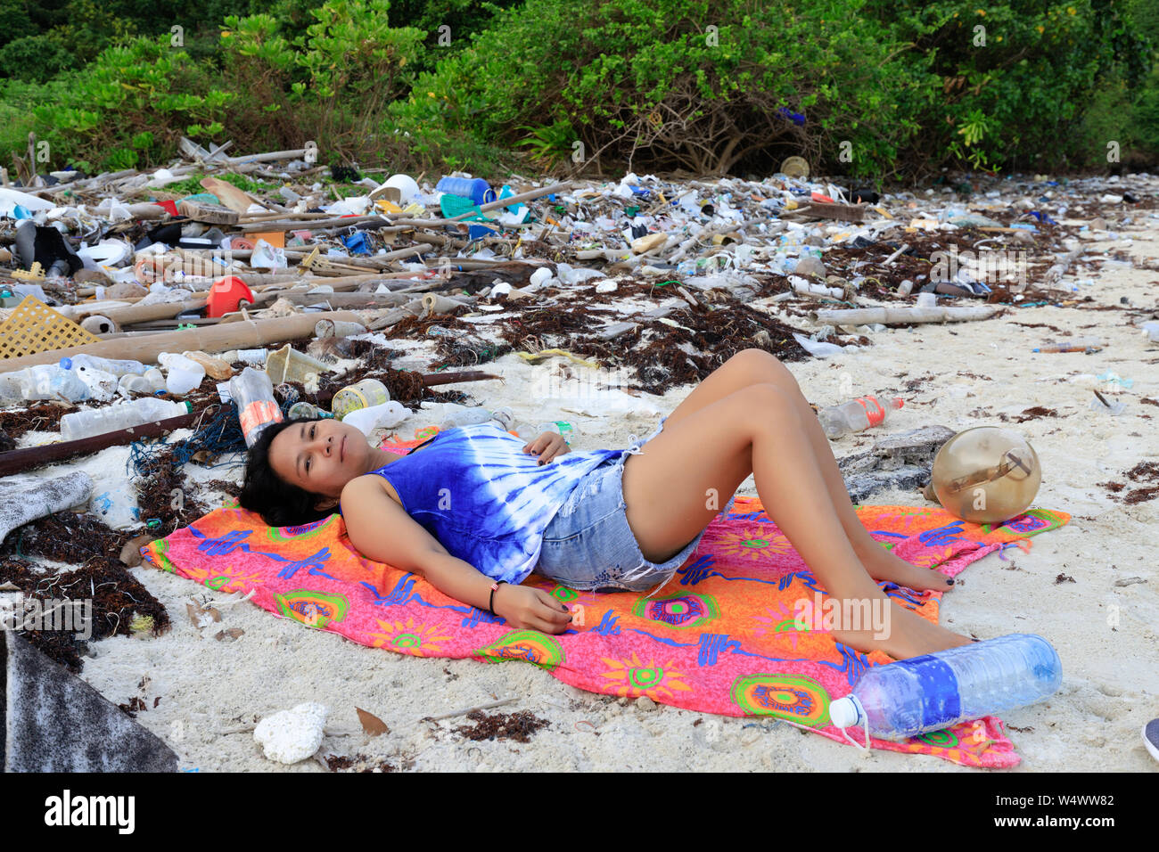 Woman relaxing on a beach very polluted by plastic pollution, Thailand Stock Photo