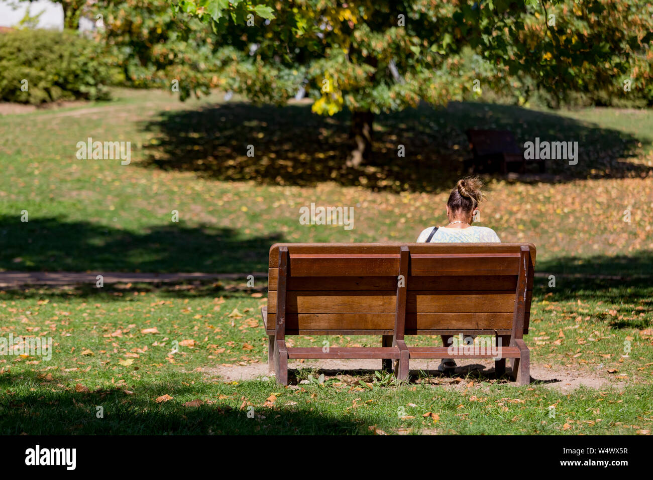 Girl sitting on park bench hi-res stock photography and images - Alamy
