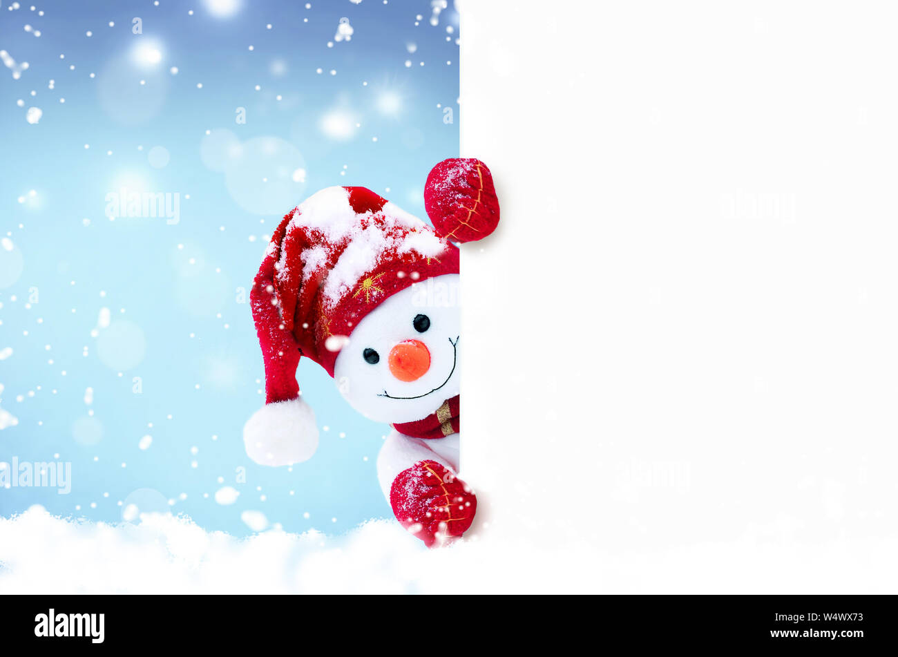 Little snowman in caps and scarfs on snow in the winter. Festive background with a funny snowman. Christmas card, copy space. Stock Photo