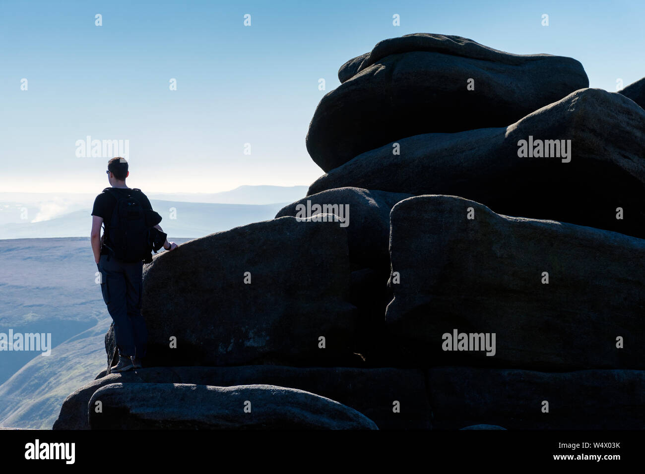 A walker at the Wool Packs rocks, on the Kinder Scout plateau above Edale, Peak District, Derbyshire, England, UK Stock Photo