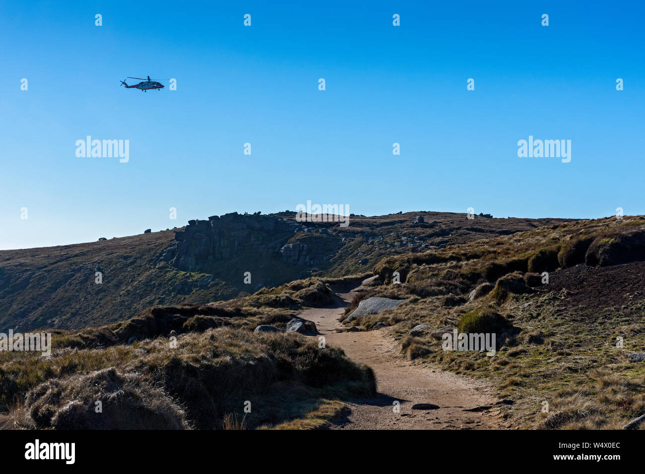 HM Coastguard search and rescue helicopter above the Kinder Scout plateau, Edale, Peak District, Derbyshire, England, UK Stock Photo