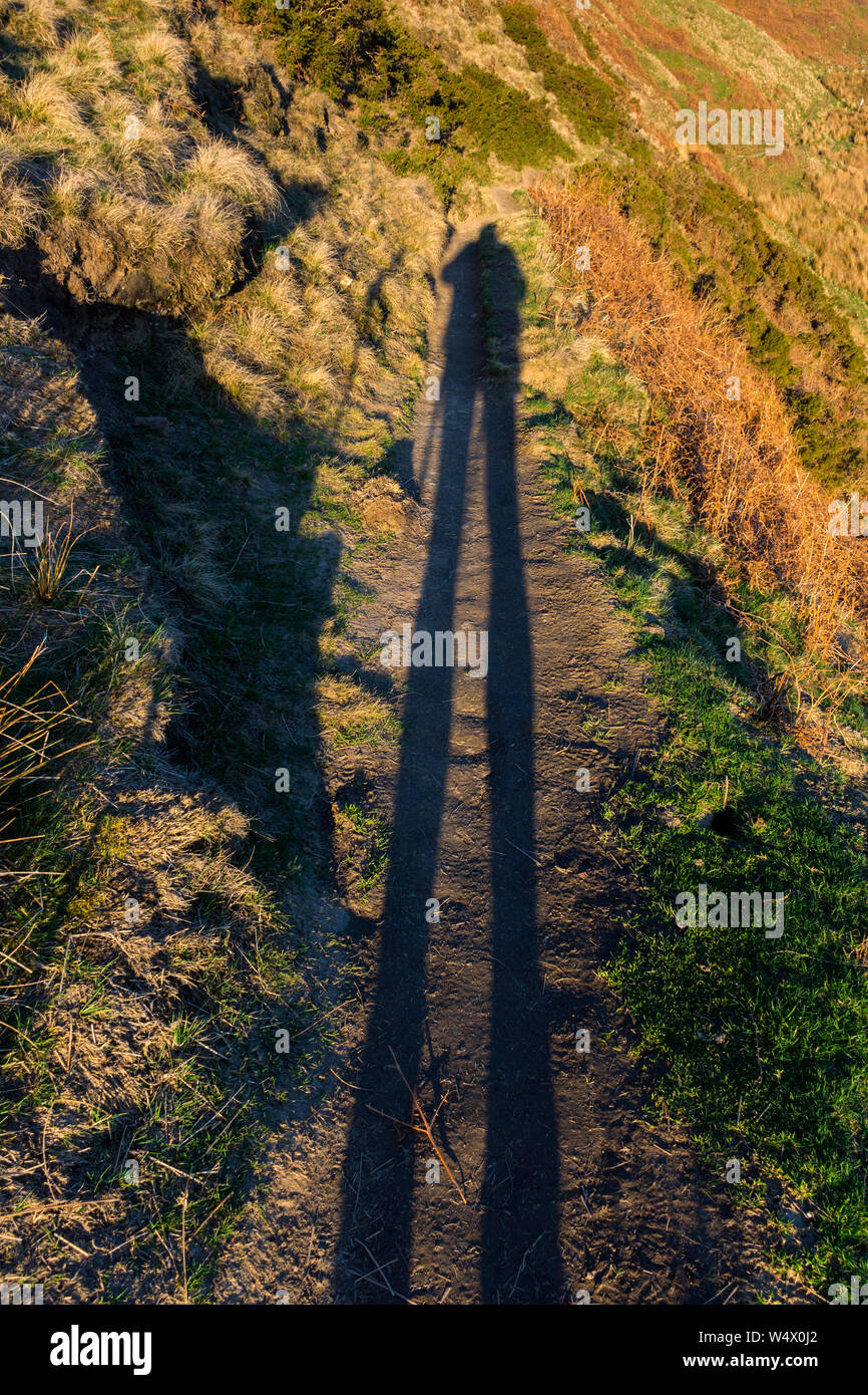 Shadow of a walker - photographer near sunset, on a footpath below Grindslow Knoll, Kinder Scout, Peak District, Derbyshire, England, UK Stock Photo