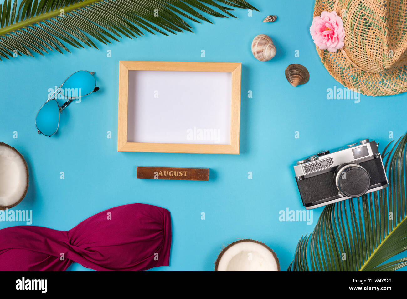 Photo frame, hat, camera, sunglasses, coconuts, on the blue background. Top view. Stock Photo