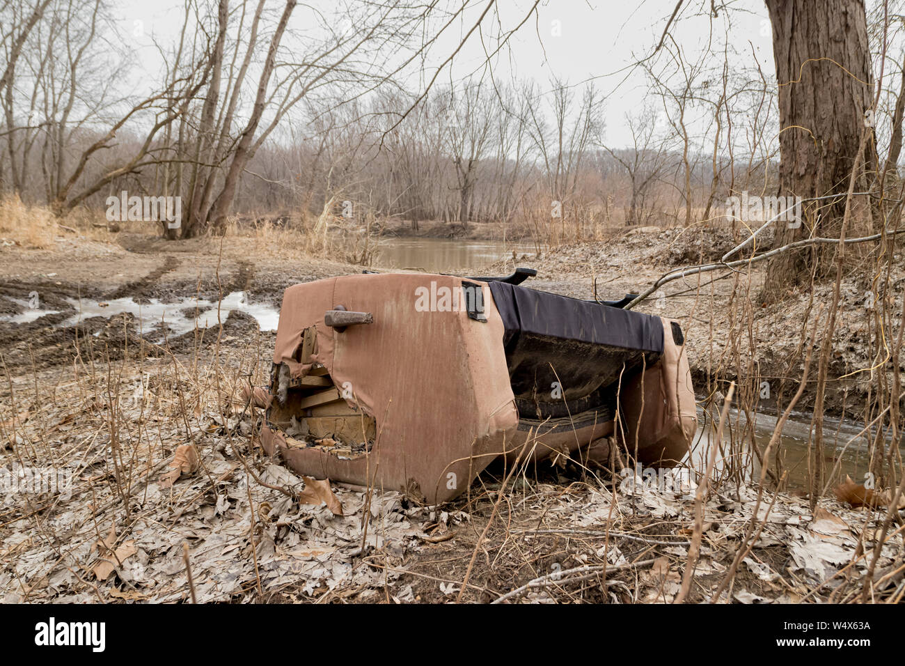 Fly dumping of recliner chair along road by river bank Stock Photo
