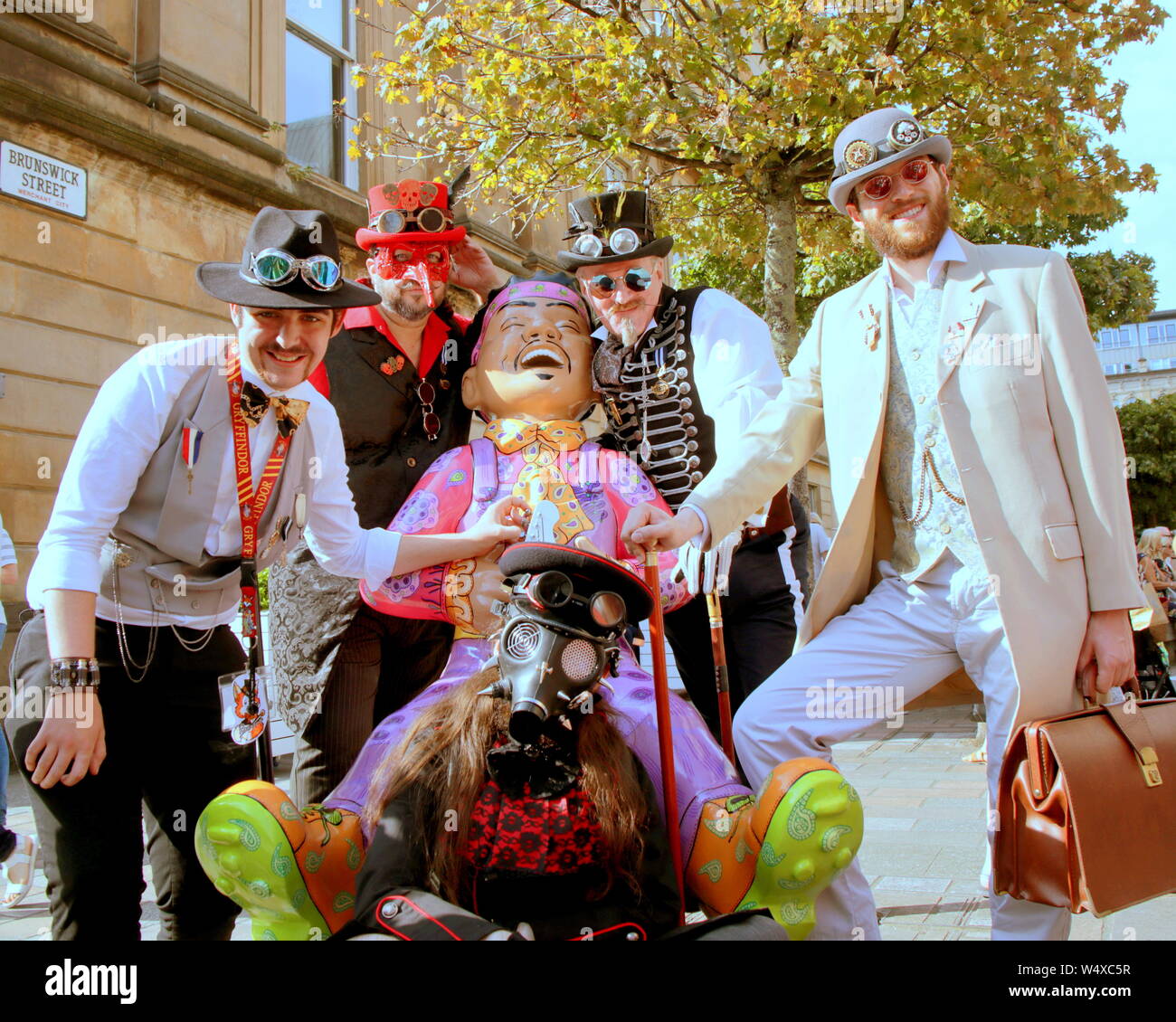 Glasgow, Scotland, UK 25th July, 2019. Sunny Merchant City Festival Masqueradeas steampunk meets the jimi hendrix oor wullie statue in merchant city carnival in streets that were too hot for the costumes. Gerard Ferry/ Alamy Live News Stock Photo