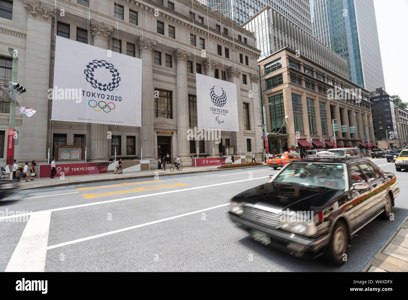 Tokyo, Japan. 25th July, 2019. Huge banners of Tokyo 2020 Olympic Games are on display outside Sumitomo Mitsui Trust Bank to promote the 2020 Tokyo Olympic and Paralympic Games. Tokyo marks one year to go 2020 Olympics decorating with Olympic emblems and photos of Japanese athletes some buildings of Nihonbashi district in Tokyo. The Games are set to open on July 24, 2020. Credit: Rodrigo Reyes Marin/AFLO/Alamy Live News Stock Photo