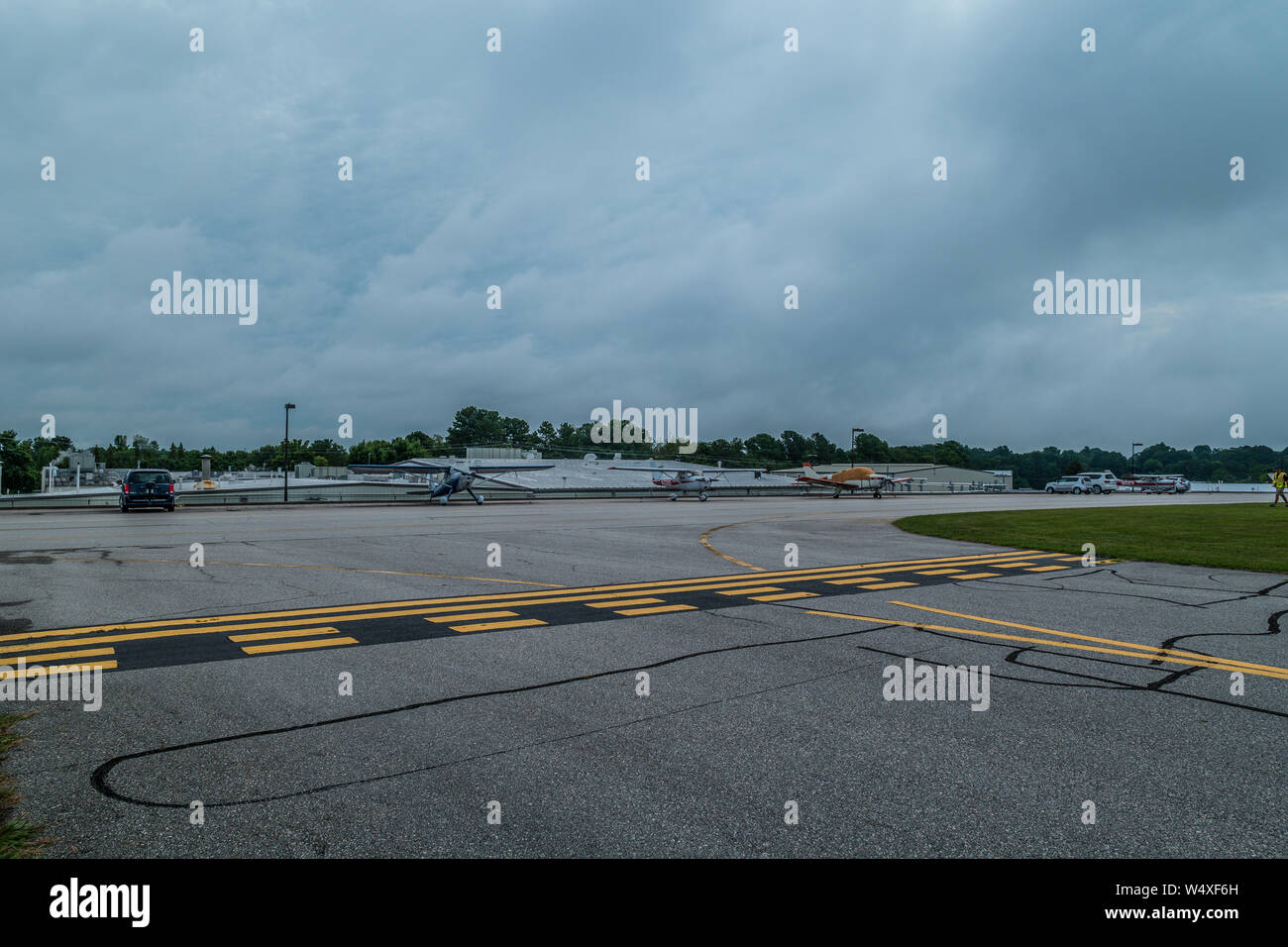 Small aircraft parked near the runway in the background at a very small airport on a cloudy day in summer Stock Photo