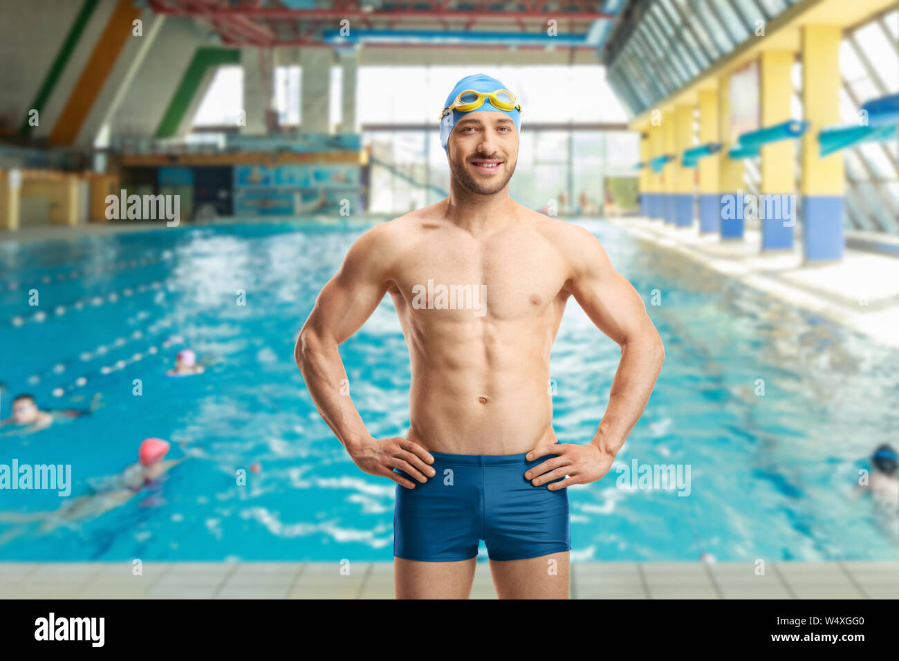 Male swimmer with cap and goggles posing at a swimming pool Stock Photo