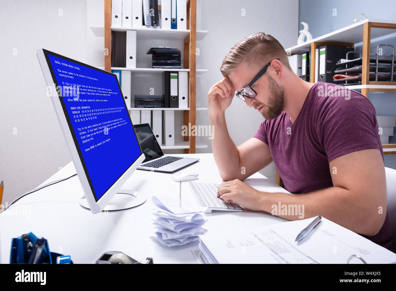 Worried Man At Computer With System Failure Screen At The Workplace Stock Photo