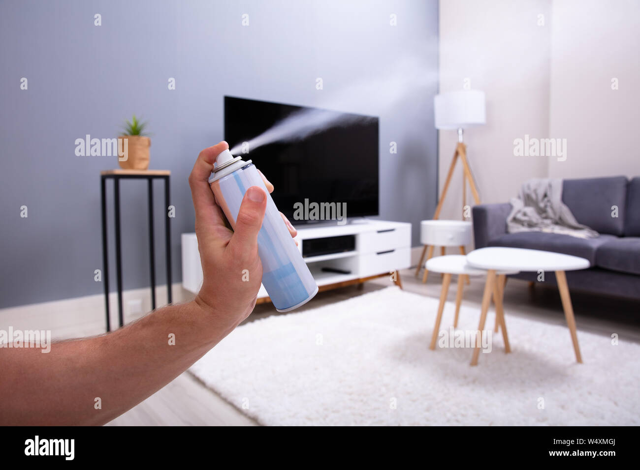 Close-up Of A Person's Hand Spraying Air Freshener In Living Room Stock Photo