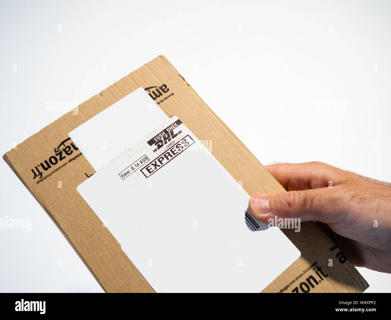Paris, France - Jun 17, 2017: Man hand holding against white bakground  Amazon parcel cardboard parcel with DHL express delivery sticker Stock  Photo - Alamy