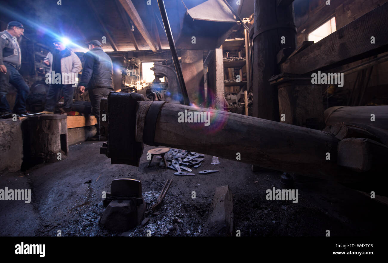 old mechanical hammer in blacksmith traditional workshop with workers ...