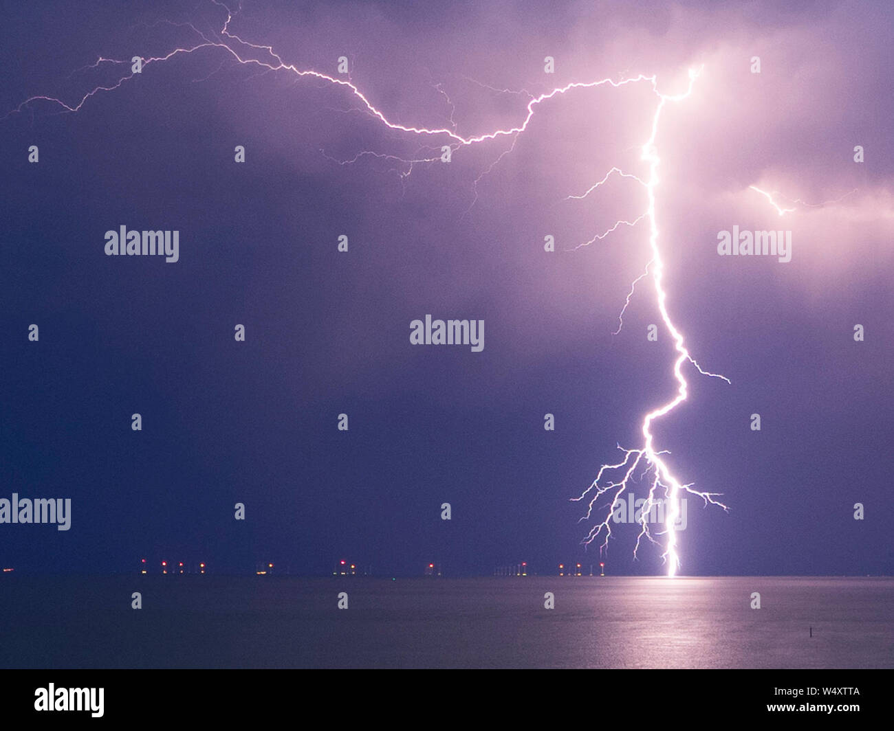 Minster on Sea, Kent, UK. 25th July, 2019. UK Weather: lightning seen over Minster on Sea in Kent. Pictured: lightning strikes just to the right of the Kentish flats windfarm. Credit: James Bell/Alamy Live News Stock Photo