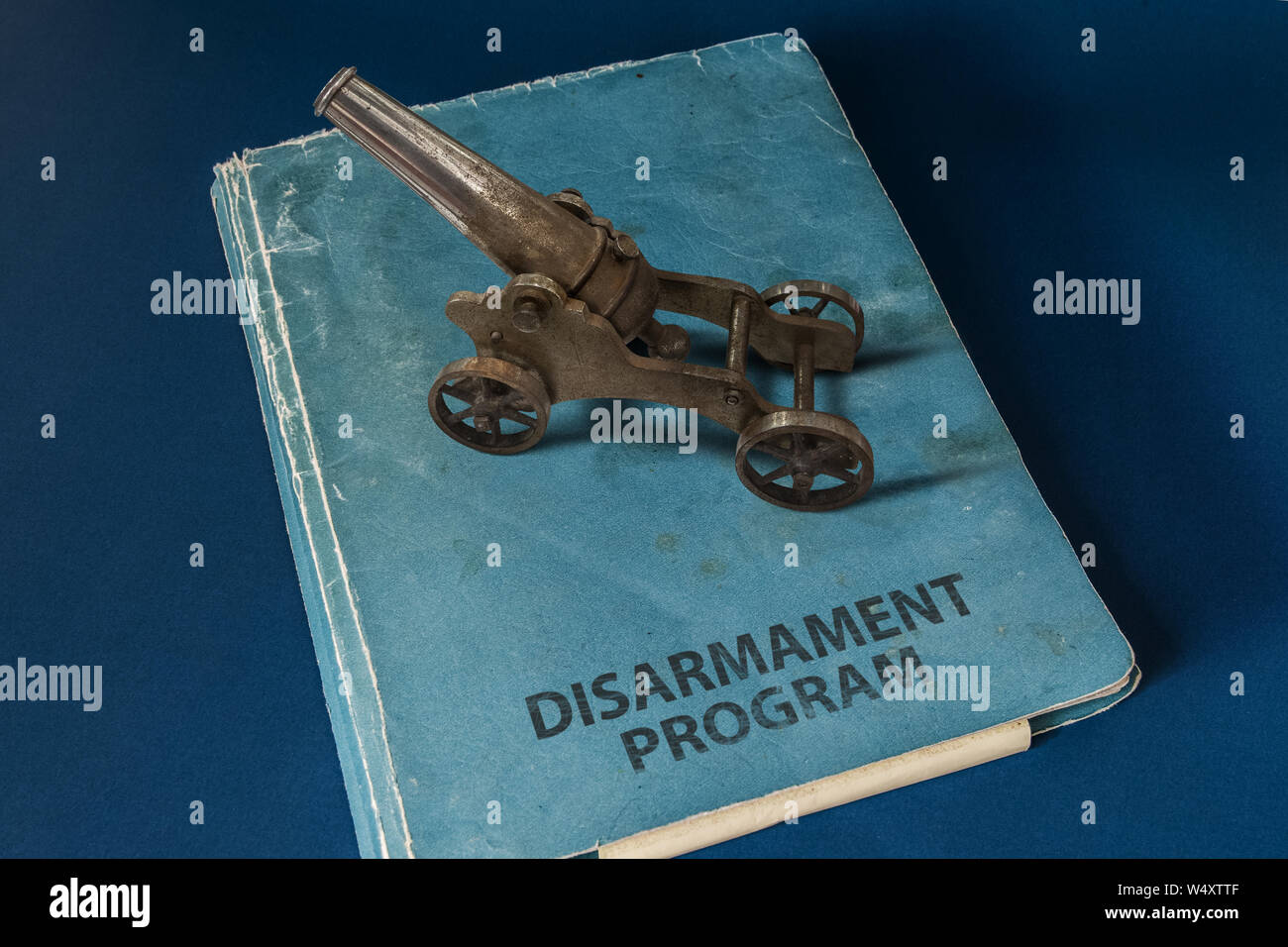 A small black powder cannon on top of a document whose title is: DISARMAMENT PROGRAM. Stock Photo