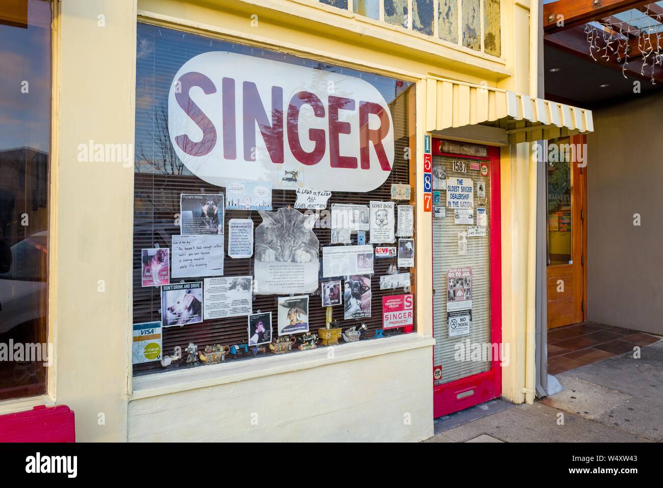Facade of Singer sewing machine dealership on Solano Avenue in Berkeley, California, with eclectic signage in shop window, including sign claiming to be oldest operating Singer dealership, December 18, 2018. () Stock Photo