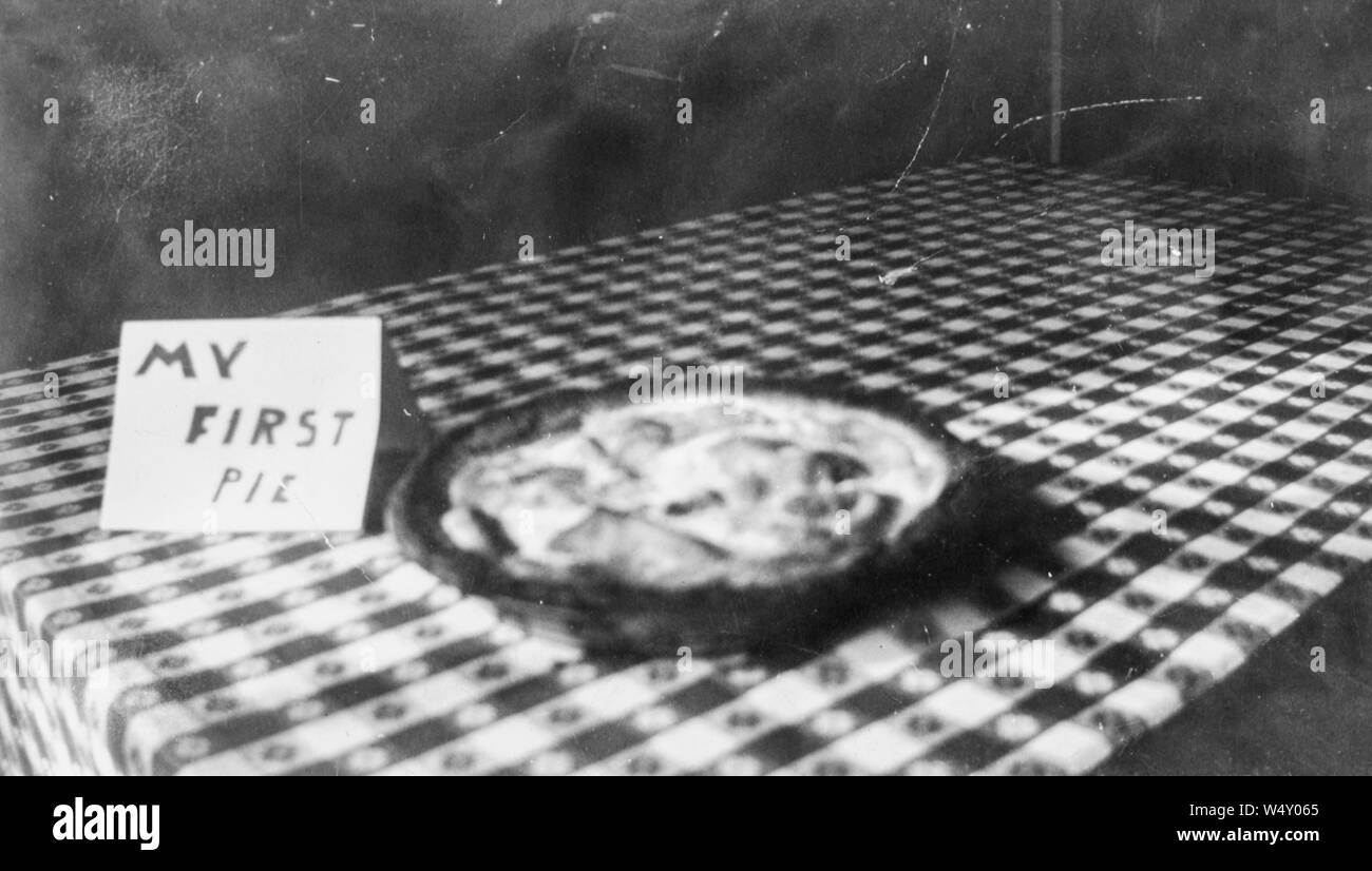 Close-up of baked pie cooling on a checkered tablecloth, with sign in child's handwriting reading My First Pie, Detroit, Michigan, 1960. () Stock Photo