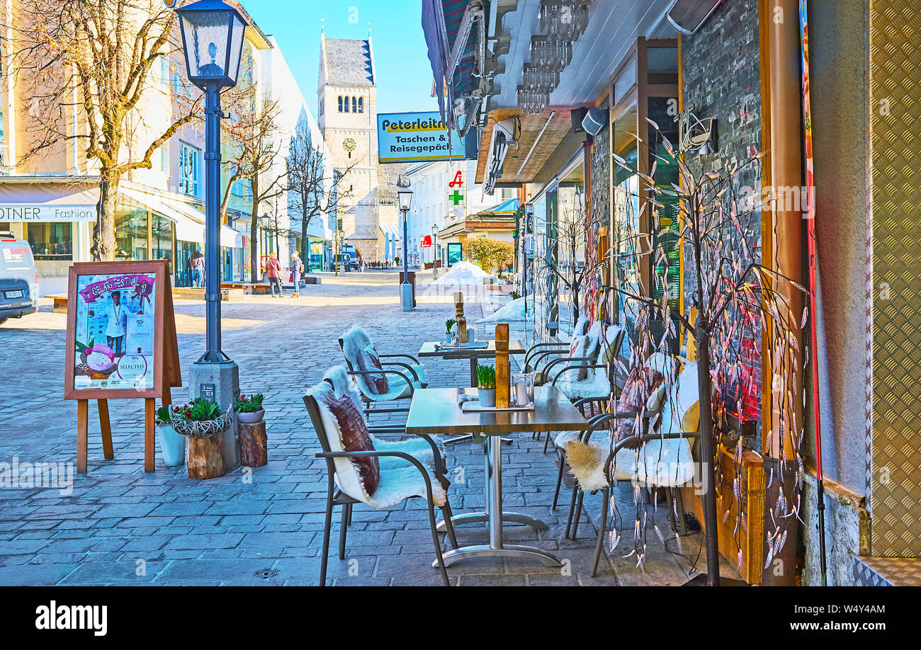 ZELL AM SEE, AUSTRIA - FEBRUARY 28, 2019: Cozy cafe in Bahnhofstrasse street with a view on stores, old townhouses and bell tower of Pfarrkirche (Pari Stock Photo