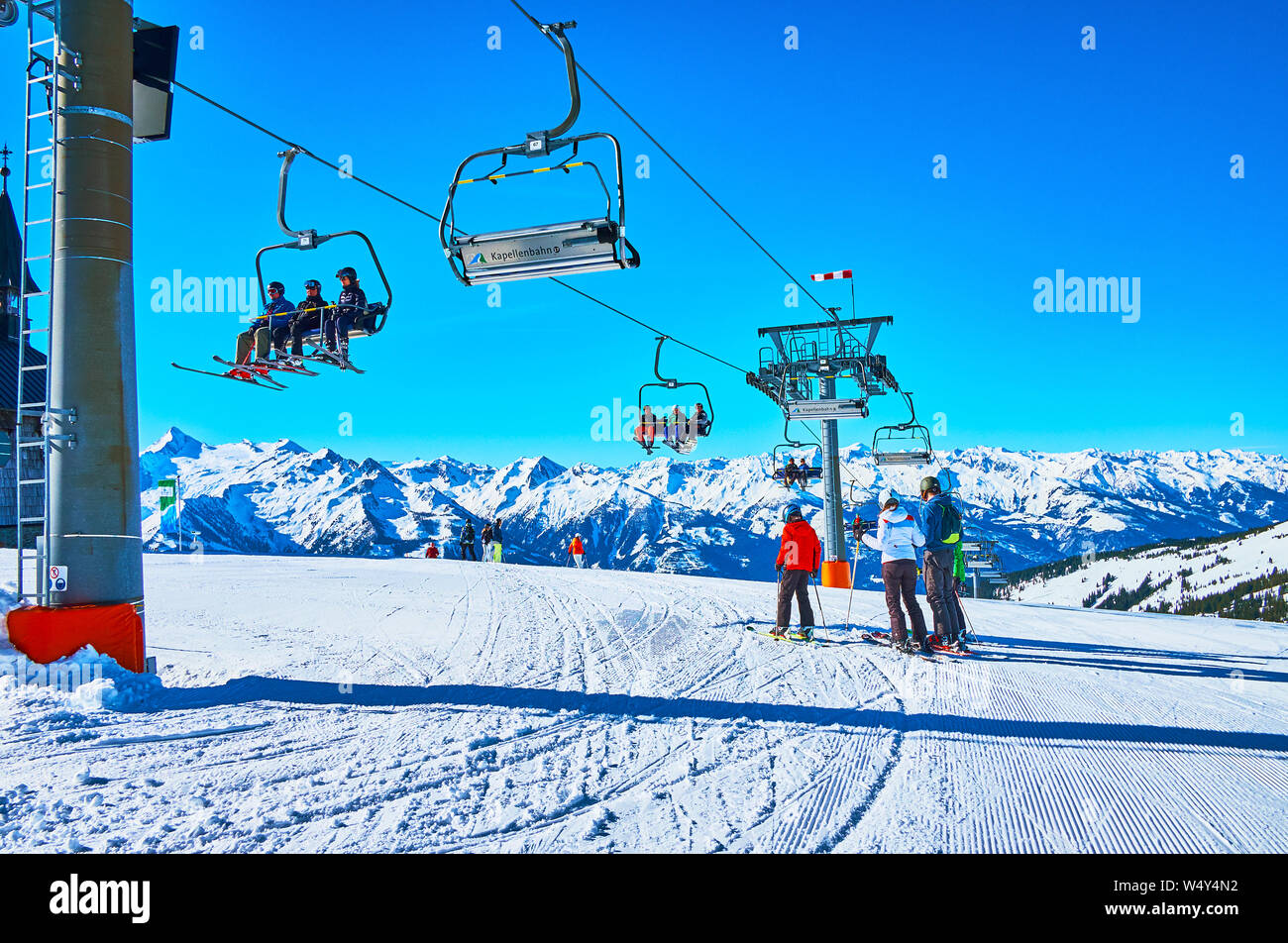ZELL AM SEE, AUSTRIA - FEBRUARY 28, 2019: Kapellenbahn chairlift with skiers and boarders rides to the top of Schmittenhohe mount, overlooking Alpine Stock Photo