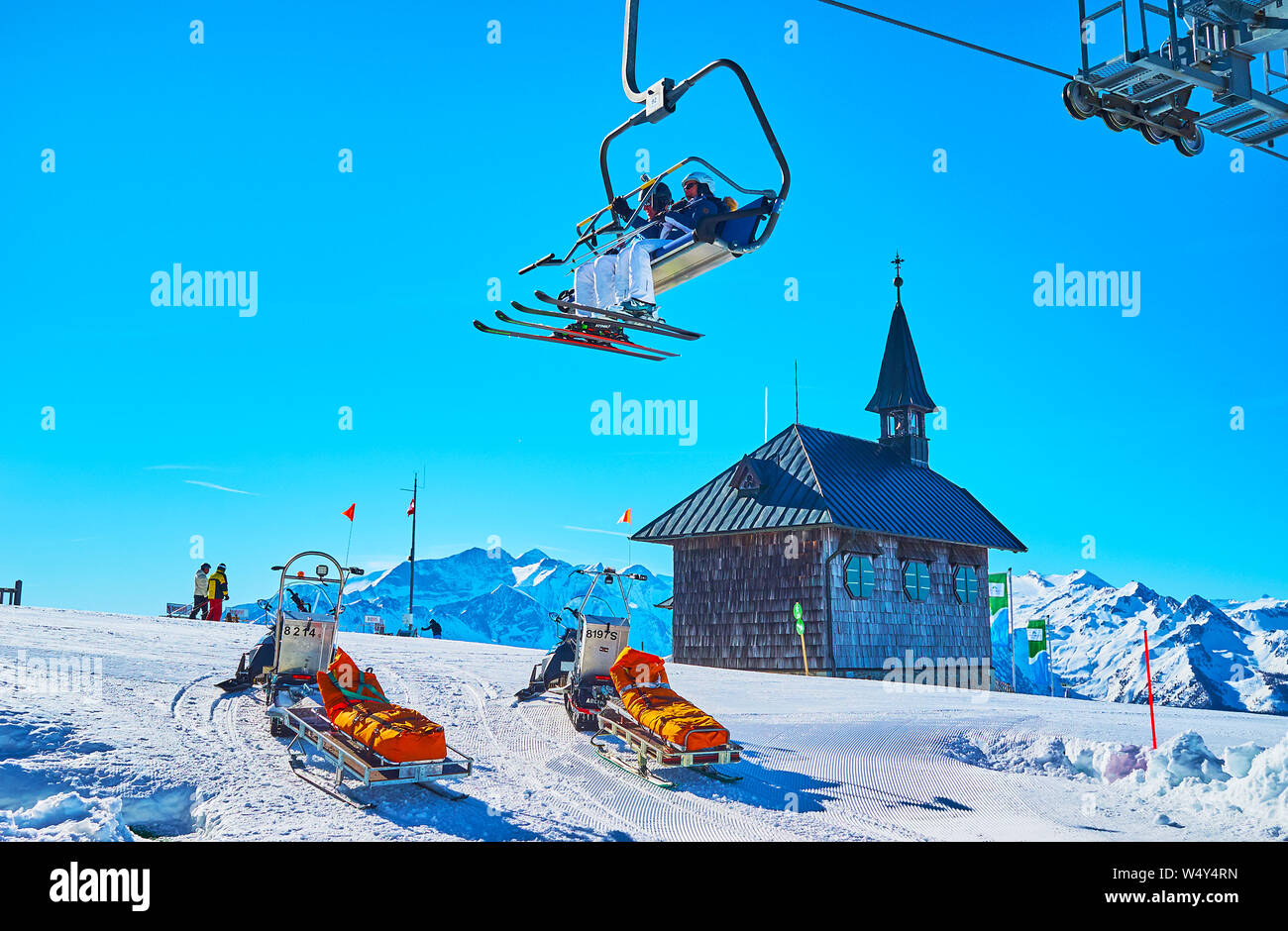 ZELL AM SEE, AUSTRIA - FEBRUARY 28, 2019: The snowbound slope of Schmittenhohe mount with a view on wooden Elisabeth chapel, rescue sleds and riding c Stock Photo