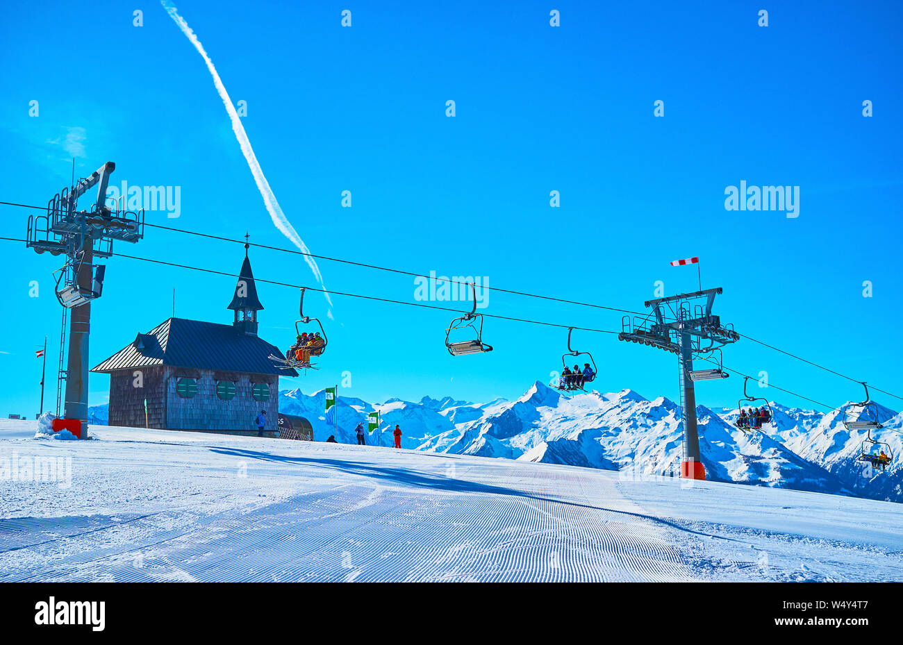 ZELL AM SEE, AUSTRIA - FEBRUARY 28, 2019: Enjoy winter landscape of Schmitten mount with corduroy groomed ski run, riding chairlift, Elisabeth chapel Stock Photo