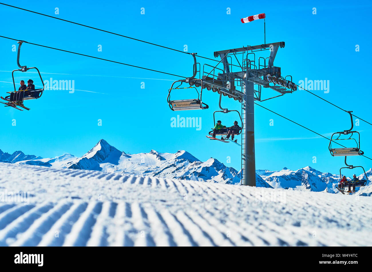 ZELL AM SEE, AUSTRIA - FEBRUARY 28, 2019: The tower and chairs of Kapellenbahn ski lift on Schmittenhohe mount with a view on groomed ski run on the f Stock Photo