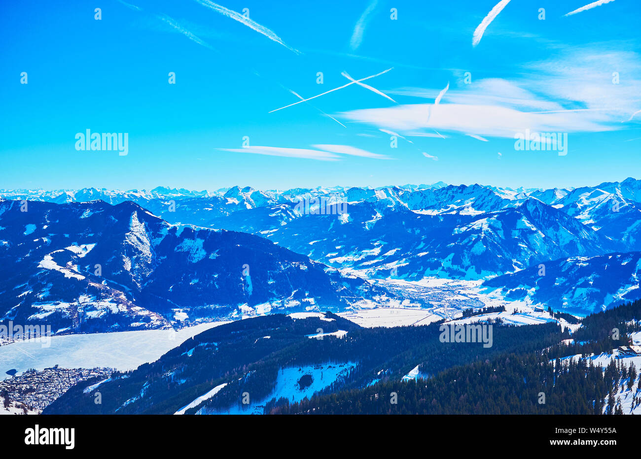 The light blue haze covers the sharp Alpine peaks and snowy slopes, seen from the peak of Schmittenhohe mount, Zell am See, Austria Stock Photo