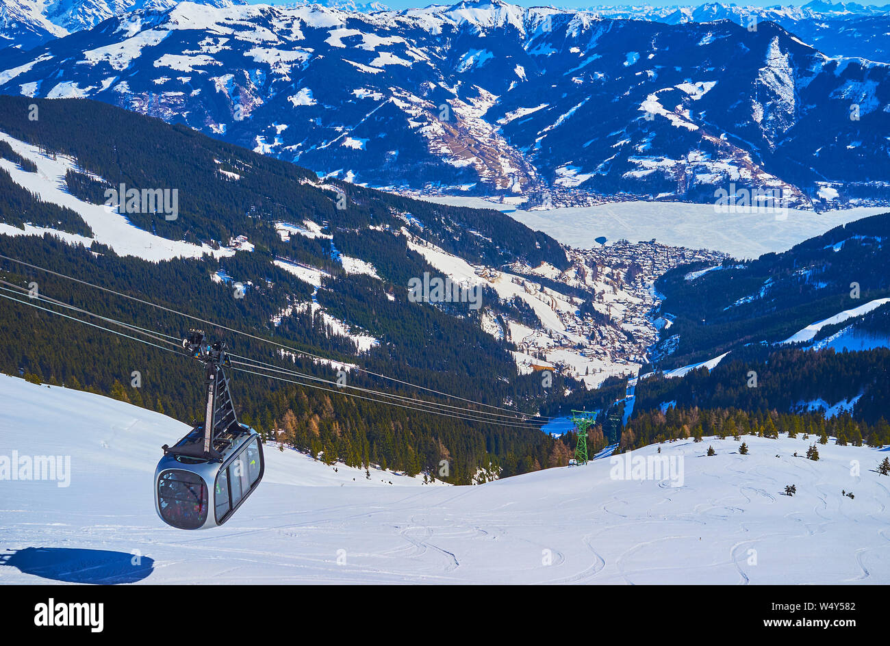 Schmittenhohe mount resort opens nice view on Zell am See valley with frozen Zeller see lake and riding modern tram of local cableway, Austria Stock Photo