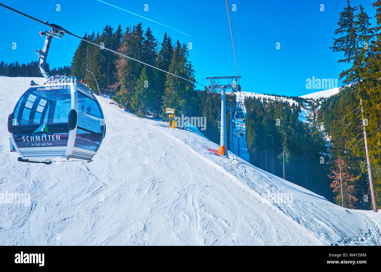 ZELL AM SEE, AUSTRIA - FEBRUARY 28, 2019: The fast gondolas of Trassxpress cable car ride along the slopes of Schmitten mount, covered with wide ski r Stock Photo