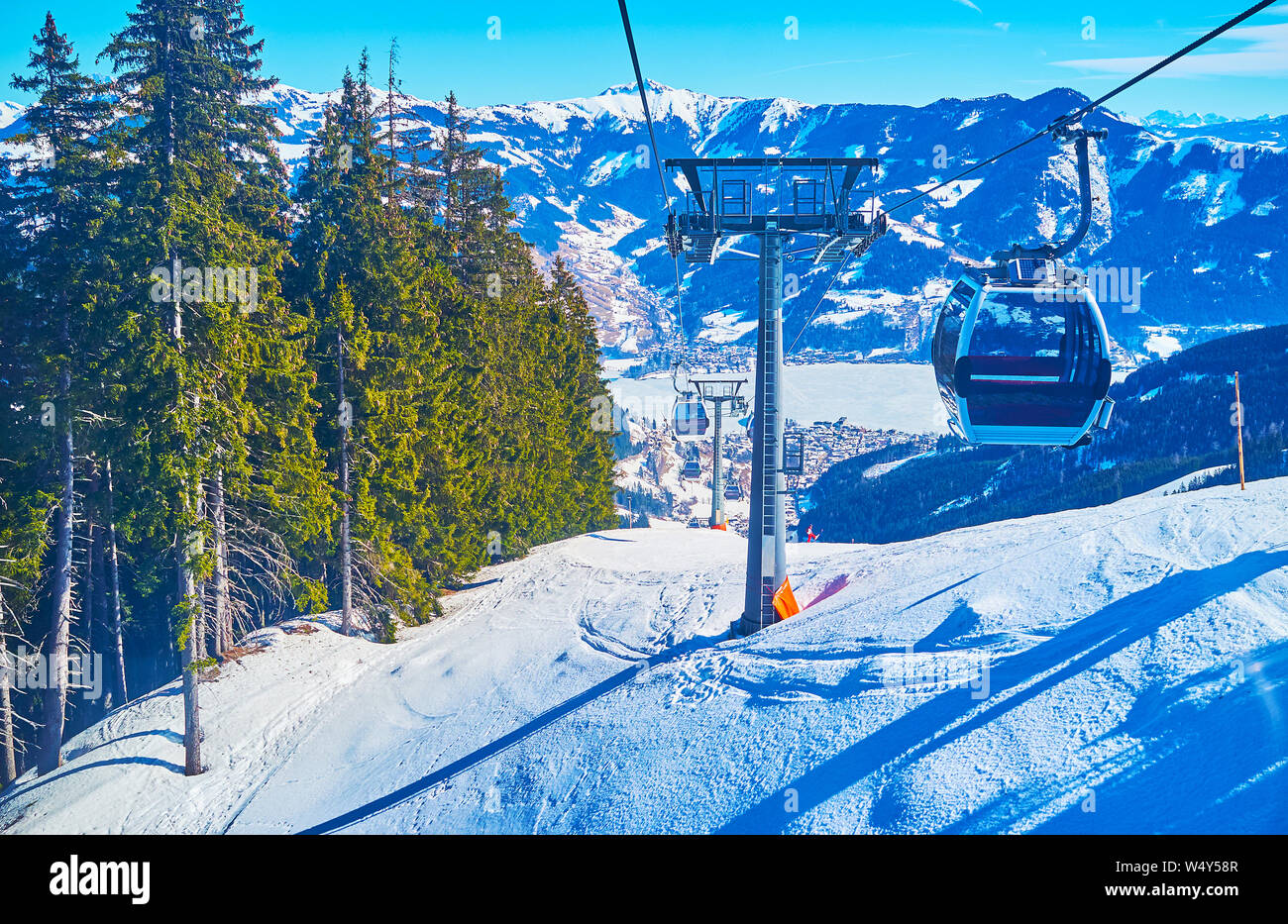 Trassxpress cableway journey is the perfect chance to overlook the slopes of Schmittenhohe mount, frozen Zeller see lake in valley, ski pistes and enj Stock Photo
