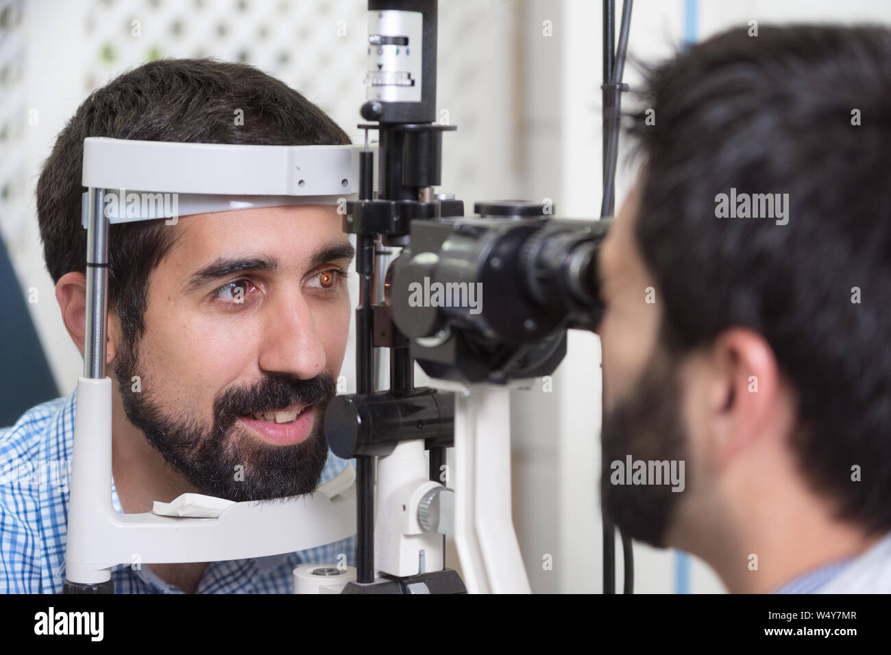 male doctor ophthalmologist is checking the eye vision of handsome