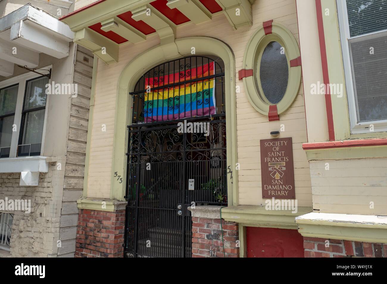 Facade with sign at monastery for Society of Saint Francis, an order of Franciscan monks in the Mission District neighborhood of San Francisco, California, with rainbow pride flag visible, July 18, 2019. () Stock Photo