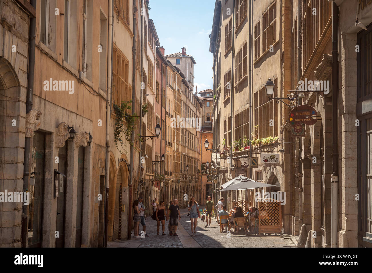 LYON, FRANCE - JULY 14, 2019: Typical narrow street of the Vieux Lyon (old Lyon) on the Presqu'ile district with tourists passing by during a sunny su Stock Photo