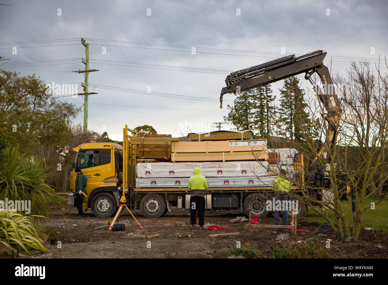 Sheffield, Canterbury, New Zealand, July 16 2019: A freight truck delivers building materials to construction site and the driver and builders unload Stock Photo