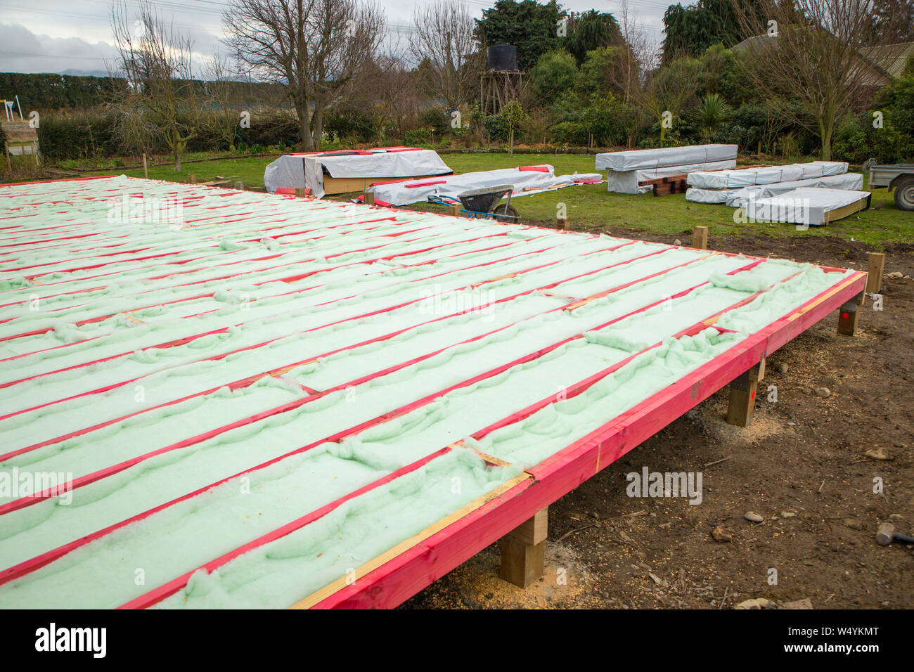 A new house floor frame is fitted with underfloor insulation on a