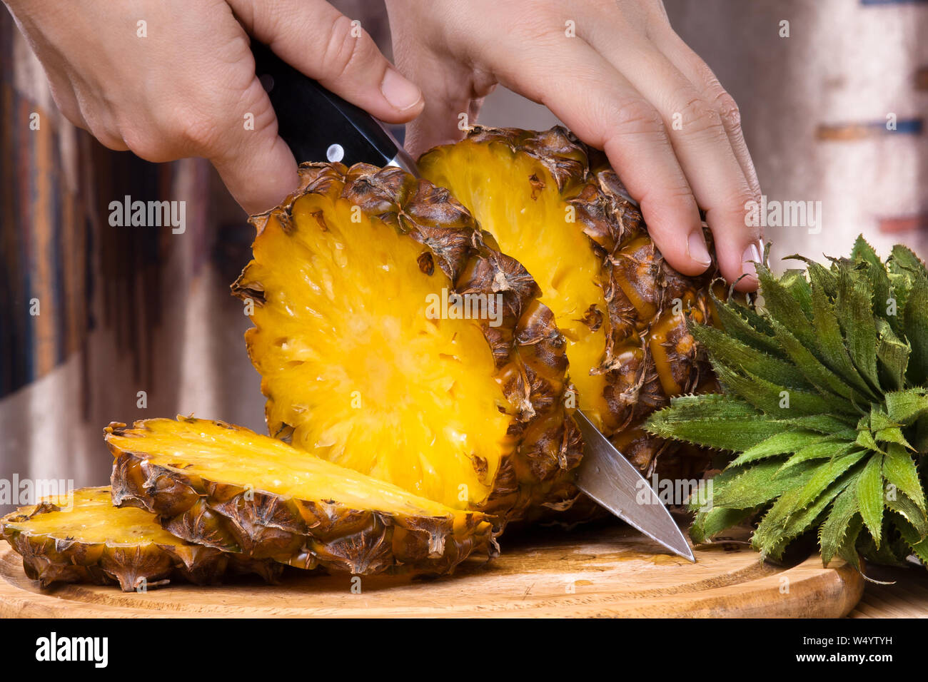 hands cutting pineapple on a cutting board, closeup Stock Photo