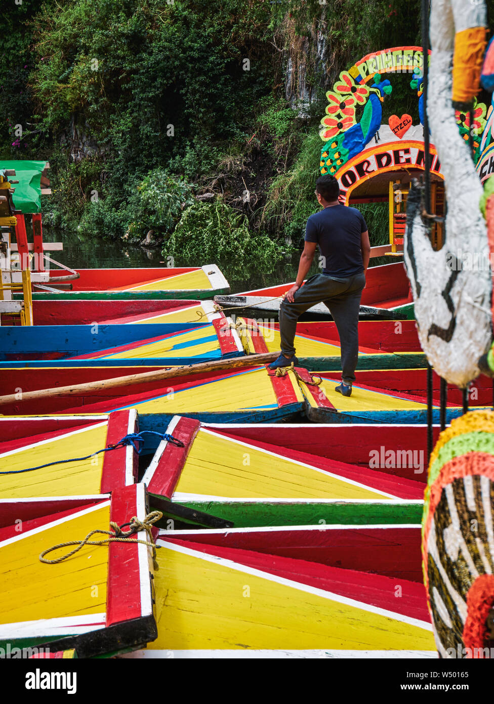 Xochimilco, Mexico City, June 25, 2019 -Man standing on the trajinera of Nativitas Emarcadero moored among other boats in Xochimilco canal. Stock Photo