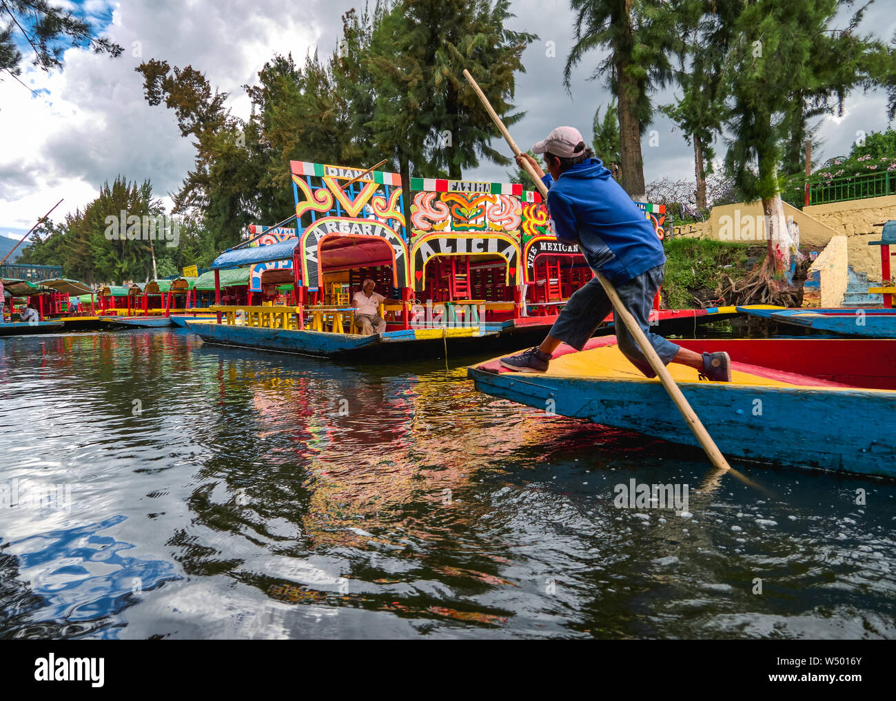 Xochimilco, Mexico City, June 25, 2019 - Young trajinero leads the trajinera with difficulty into Xochimilco canal. Stock Photo
