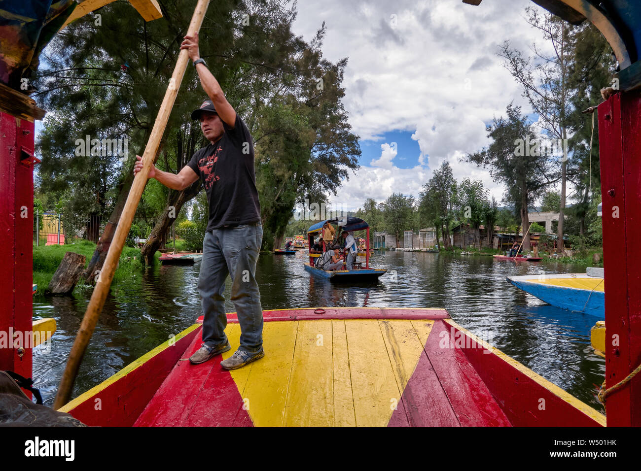 Xochimilco, Mexico City, June 25, 2019 - Man rows and leads the trajinera with tourist in Xochimilco canal. Stock Photo