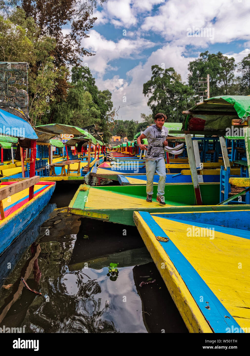 Xochimilco, Mexico City, June 25, 2019 - Boy jump from one trajineras to another moored in Nativitas Embarcadero in Xochimilco. Stock Photo