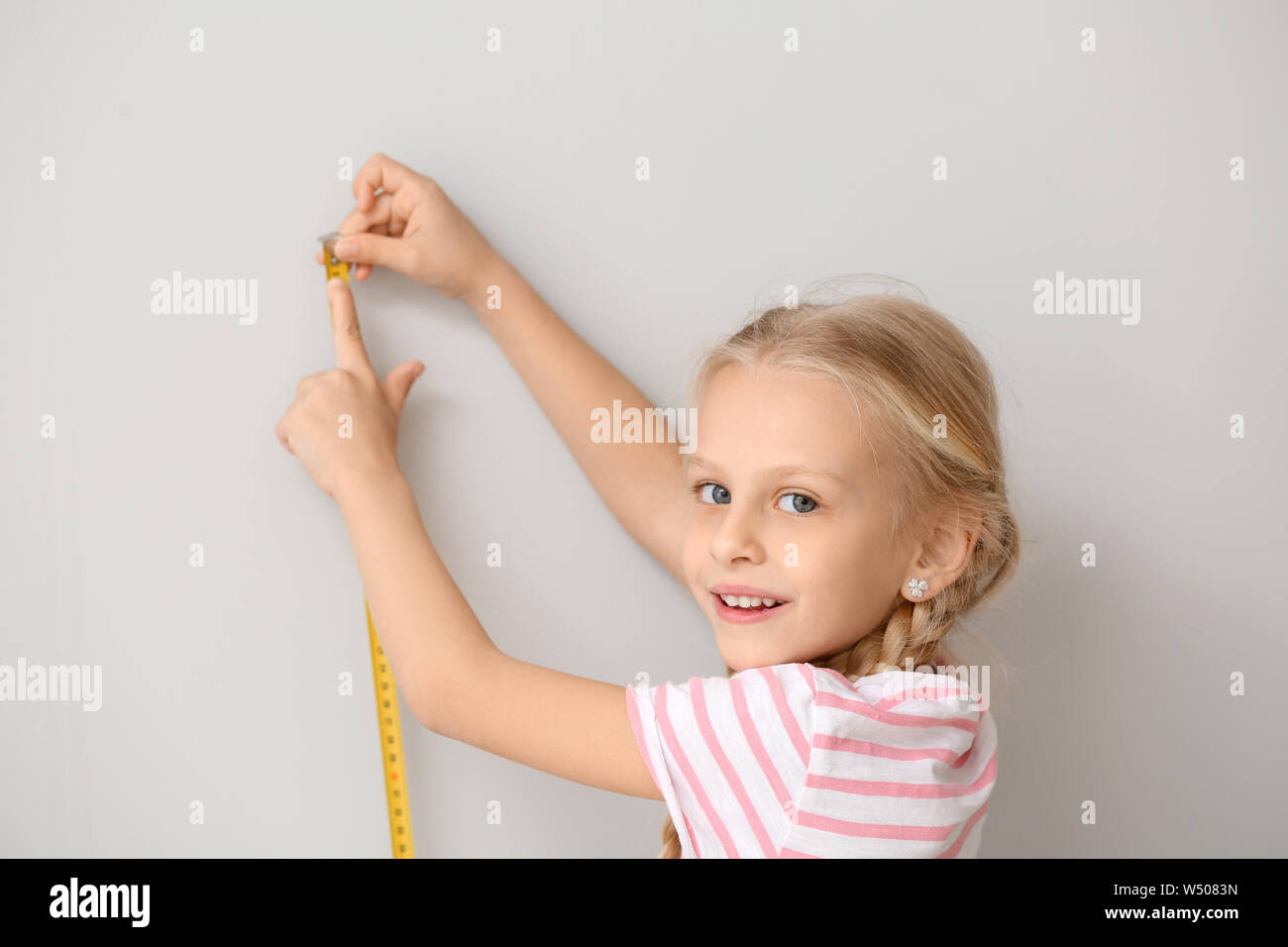 Cute little girl measuring height near wall Stock Photo