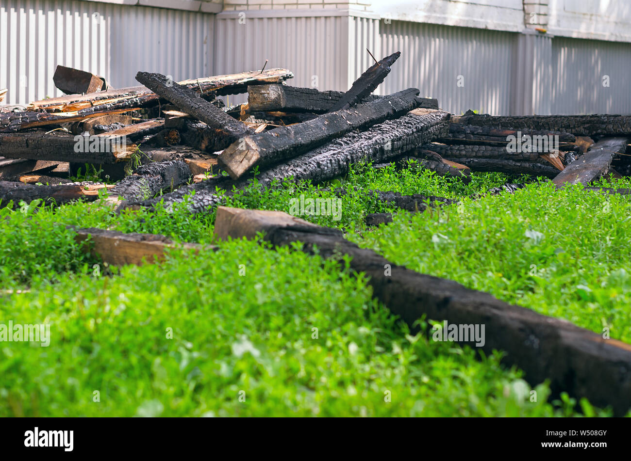 The Black Charred Rafters, Roof Framework, Nails Sticking Out Dumped on the Lawn near the Apartment Building After the Fire. Insurance Concept. Stock Photo