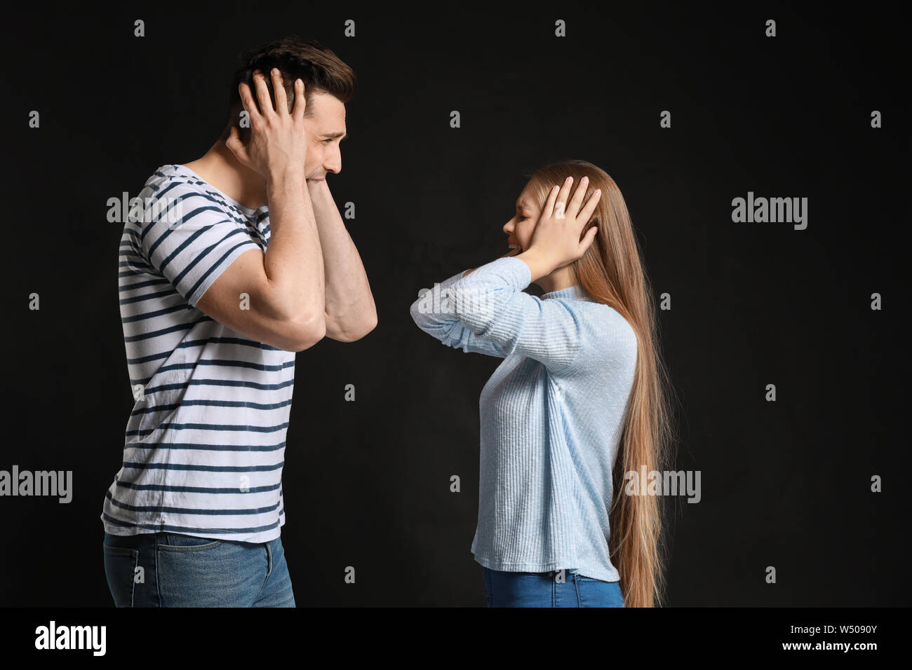 Young quarrelling couple on dark background Stock Photo