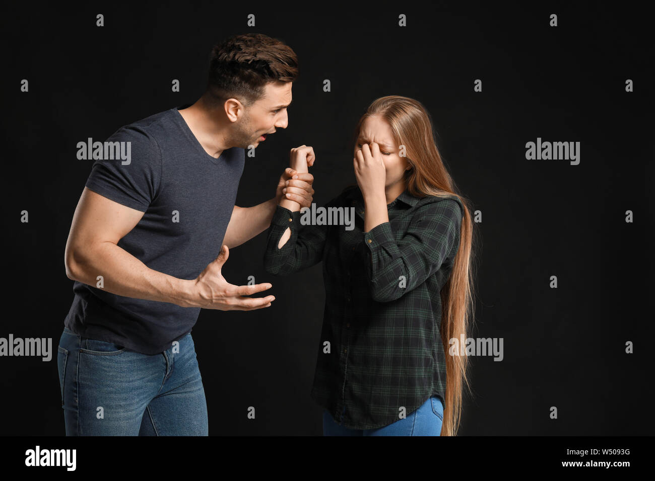 Young quarrelling couple on dark background Stock Photo