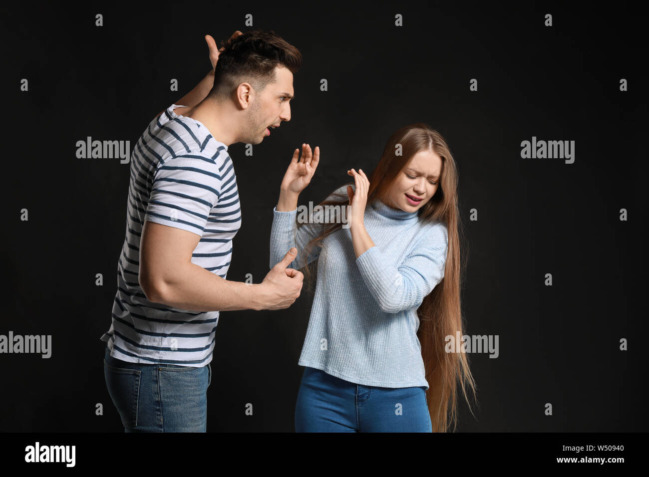 Young quarrelling couple on dark background Stock Photo